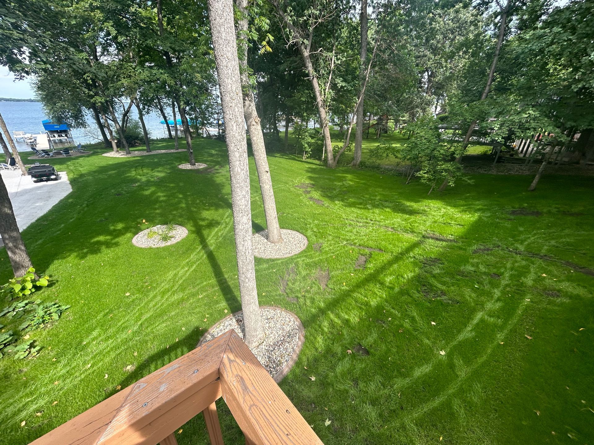 A view of a lush green lawn and trees from a deck.