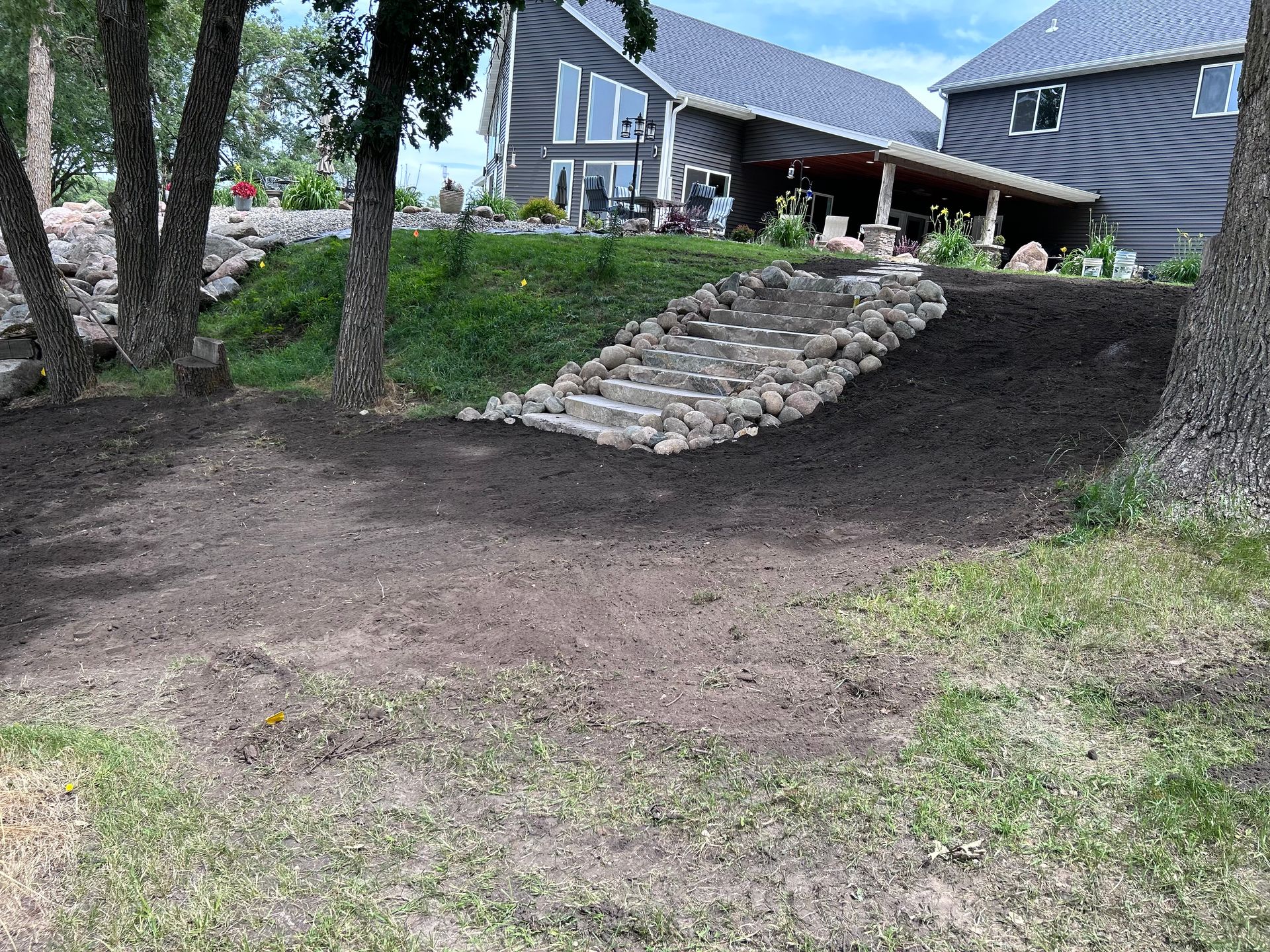 A large house is sitting on top of a hill next to a dirt field.