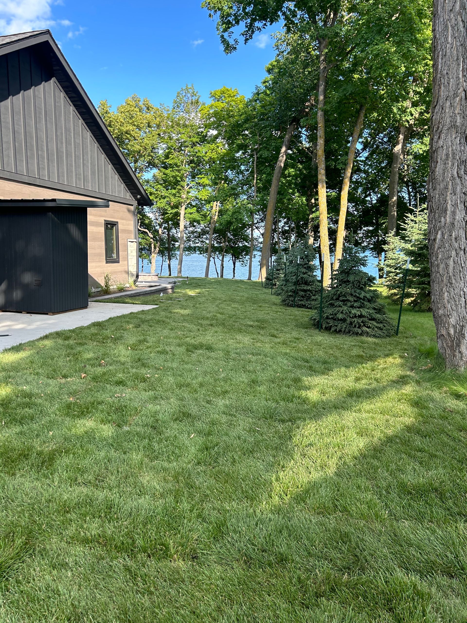 A house with a large lawn in front of it and trees in the background.