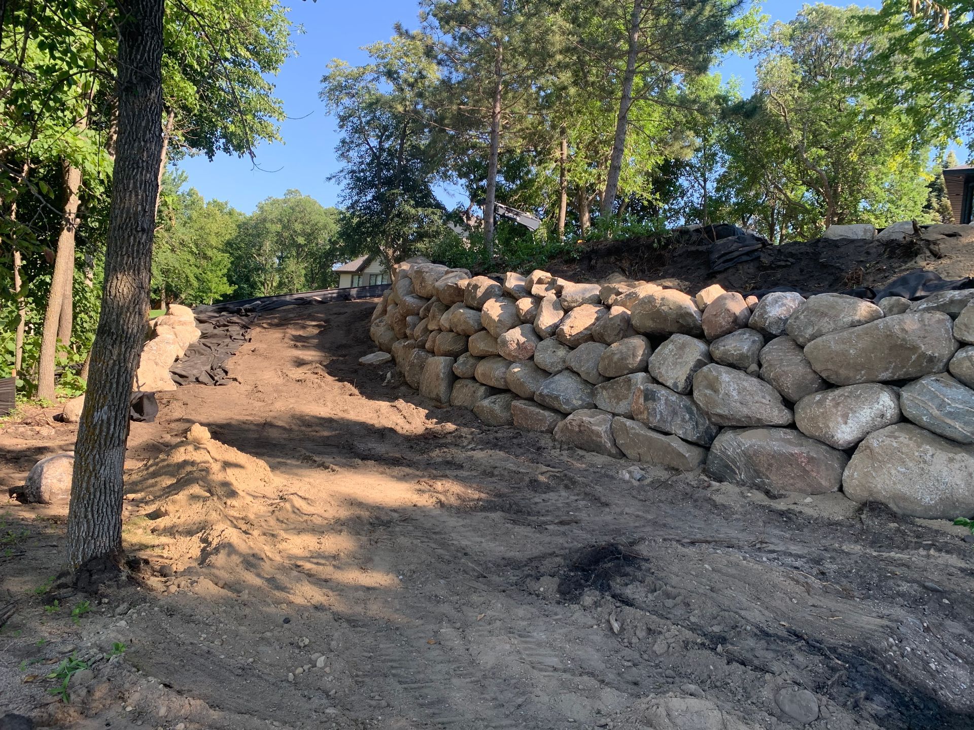 A stone wall is being built on the side of a dirt road.