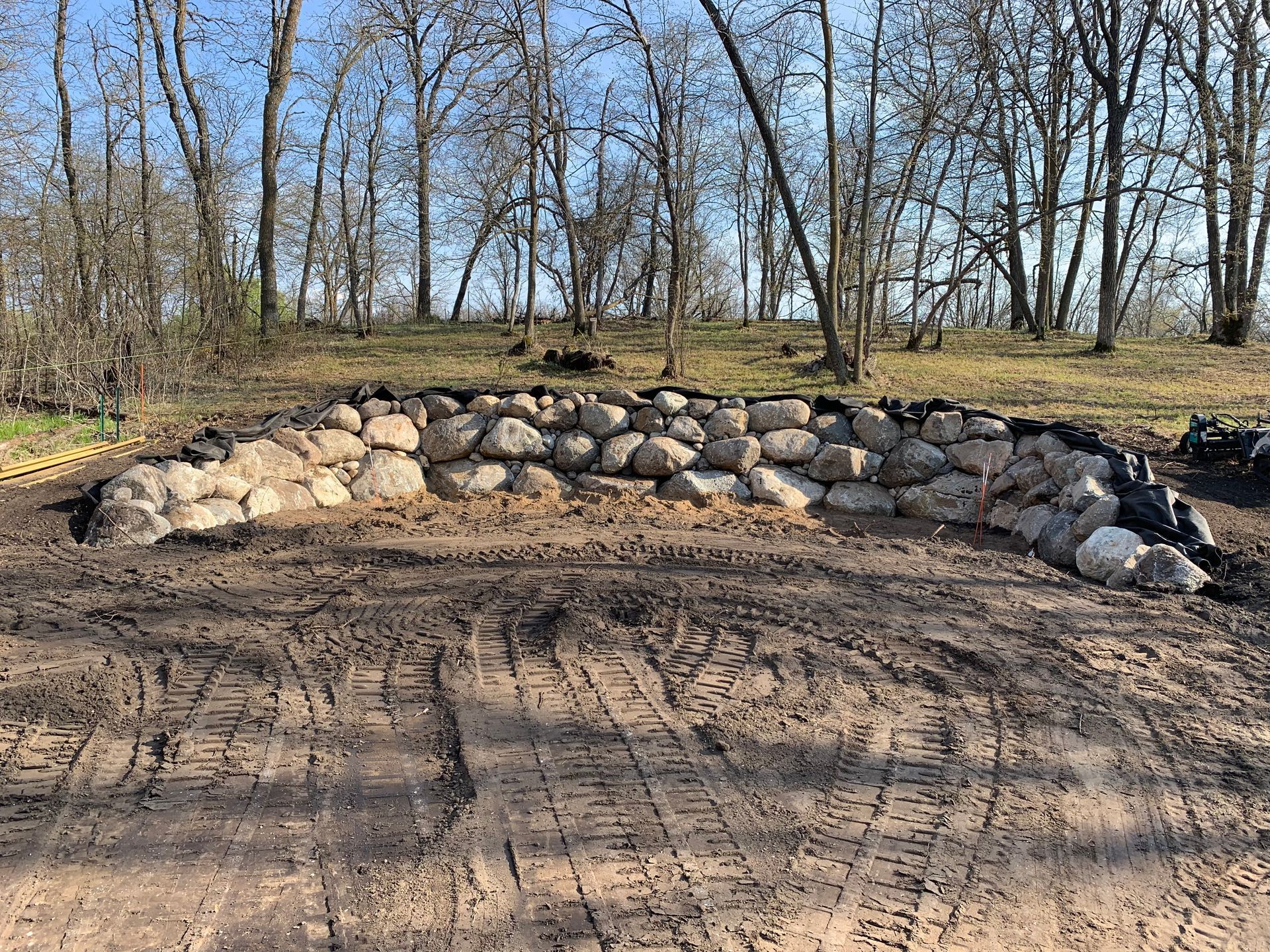 A rock wall is being built in the middle of a dirt road.