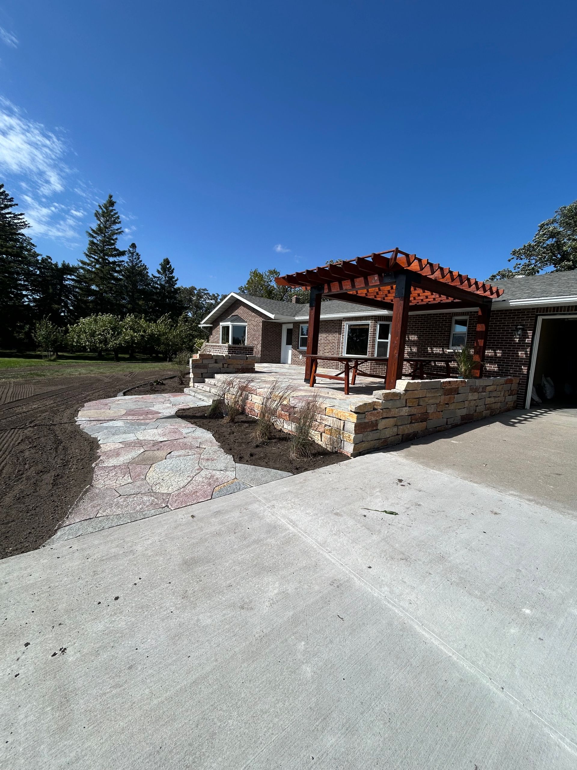 A house with a pergola and a walkway in front of it.