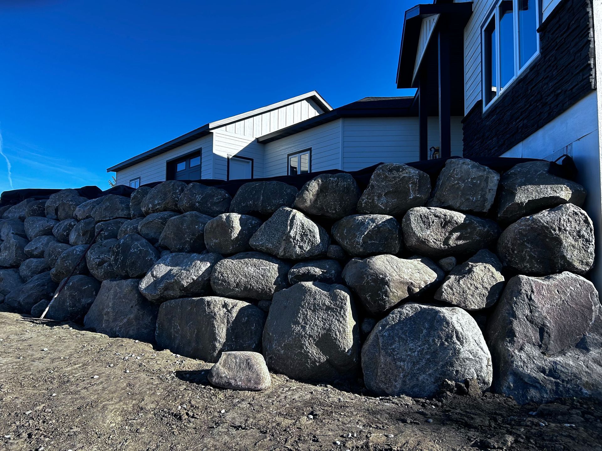 A large rock wall with a house in the background