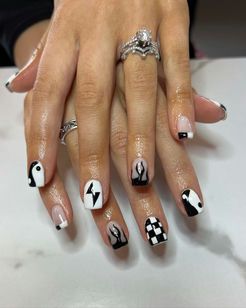 A woman 's hand with black and white nails and a ring on her finger.