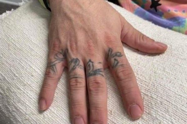 A close up of a person 's hand with a tattoo on their fingers.