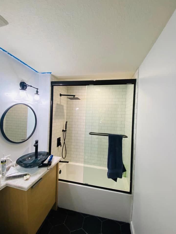 Modern bathroom with a glass shower, round mirror, wood vanity, and dark blue towels