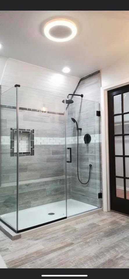 Modern bathroom with glass walk-in shower, tiled walls, and a round ceiling light