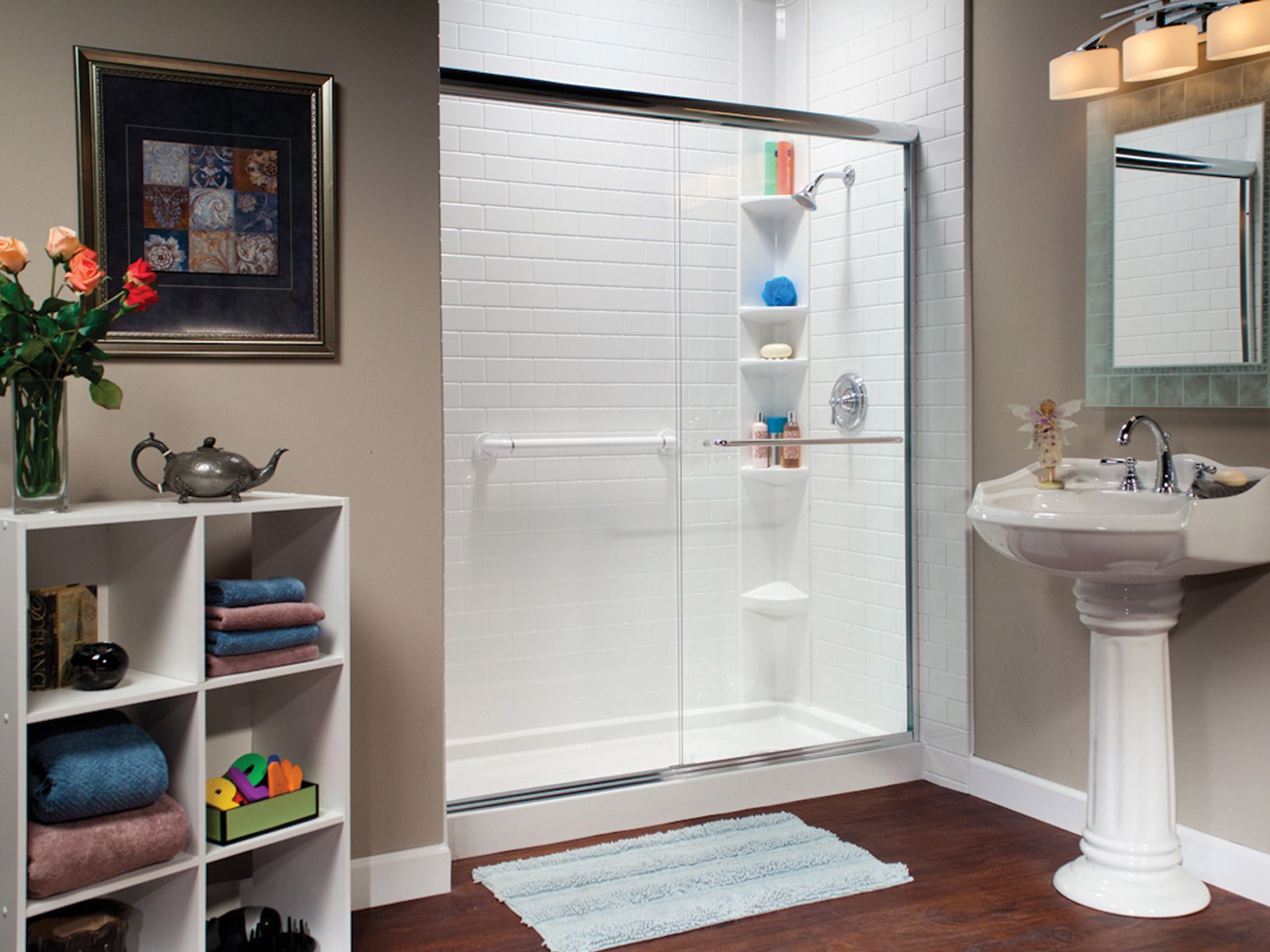 Modern bathroom with glass shower, white sink, shelving, and a striped bath mat