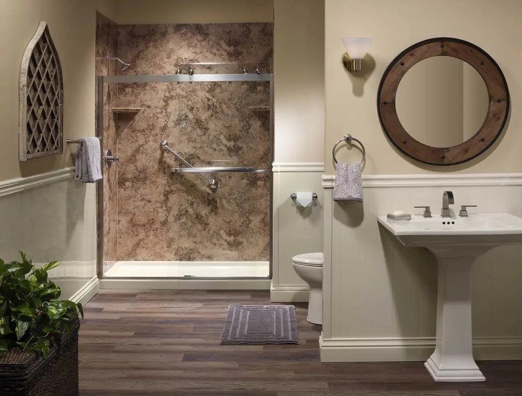 Modern bathroom with walk-in shower, pedestal sink, round mirror, and wood-look floor