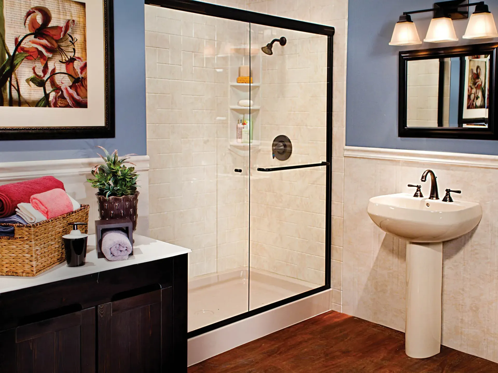 Bathroom with glass shower, pedestal sink, dark vanity, and wall art in blue and white decor