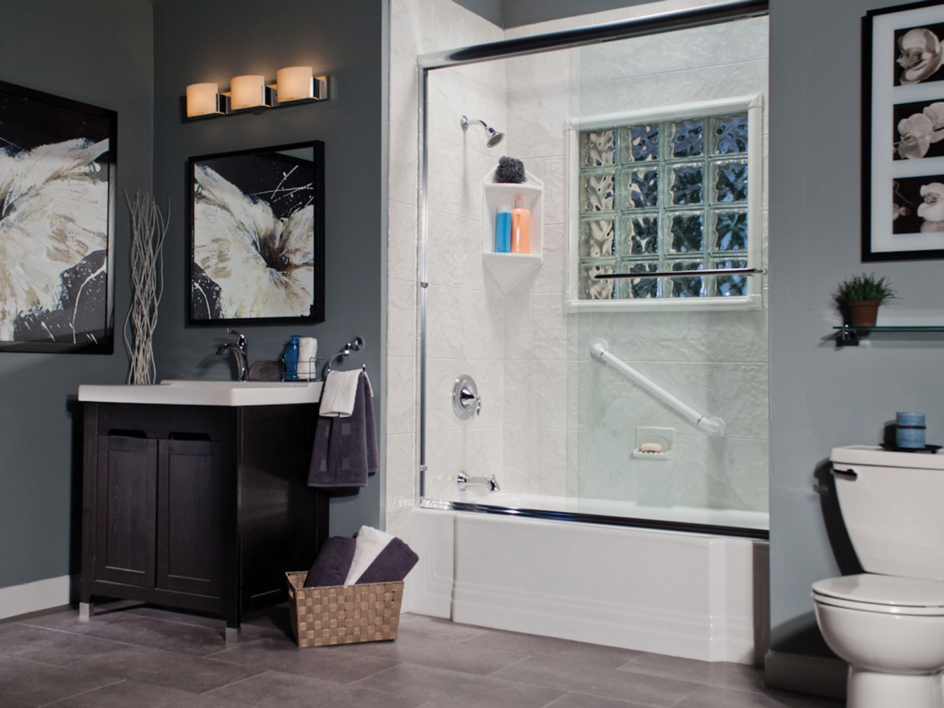 Modern bathroom with a glass shower, dark vanity, and toilet on a gray wall.