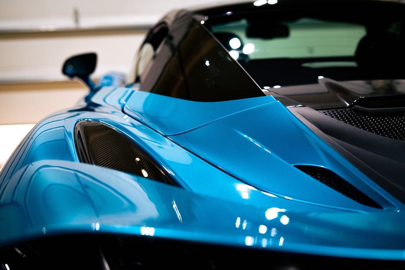 Blue sports car's front with a black windshield, and air vents.