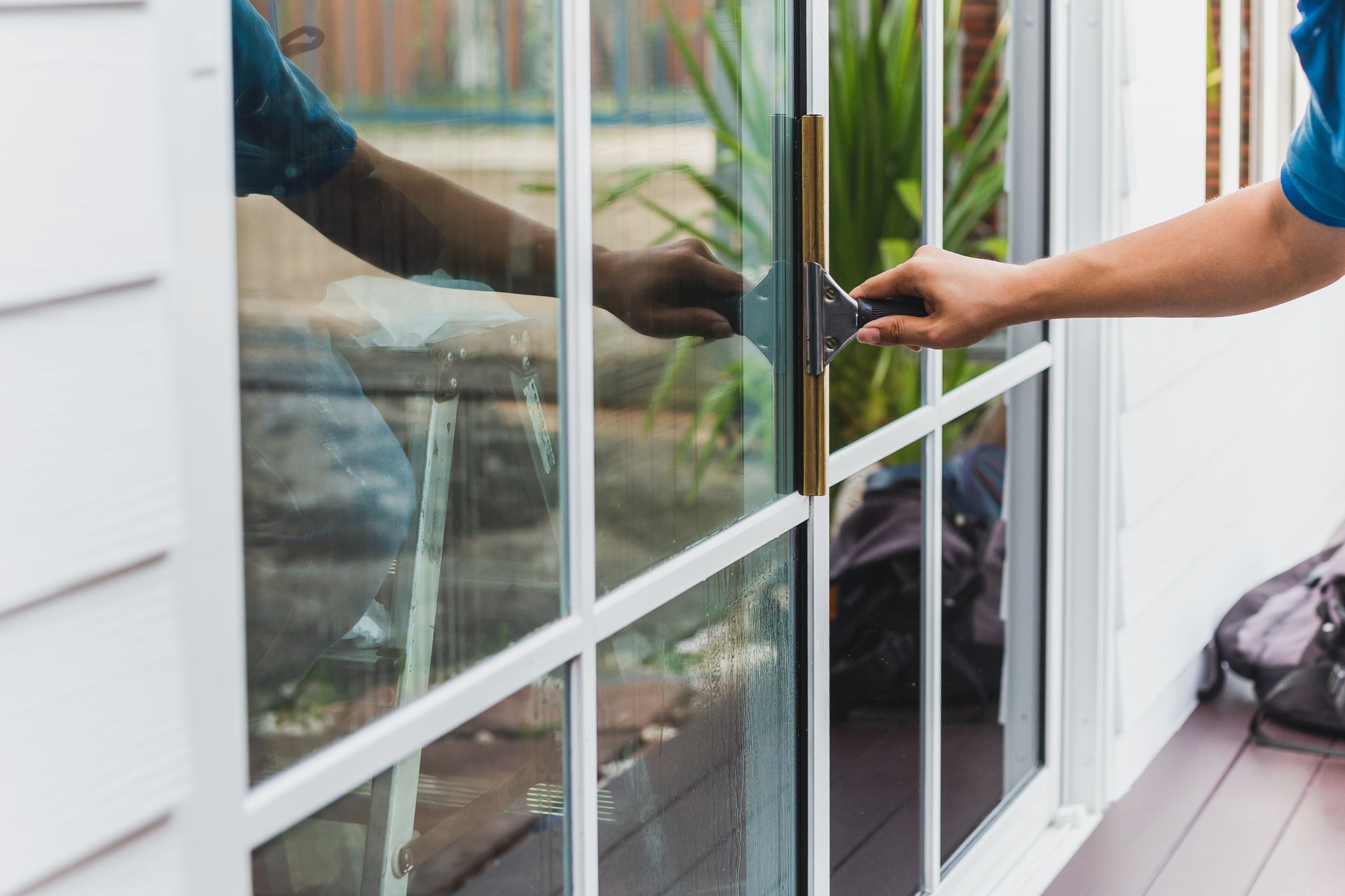 Person cleaning a glass door with a squeegee outdoors.
