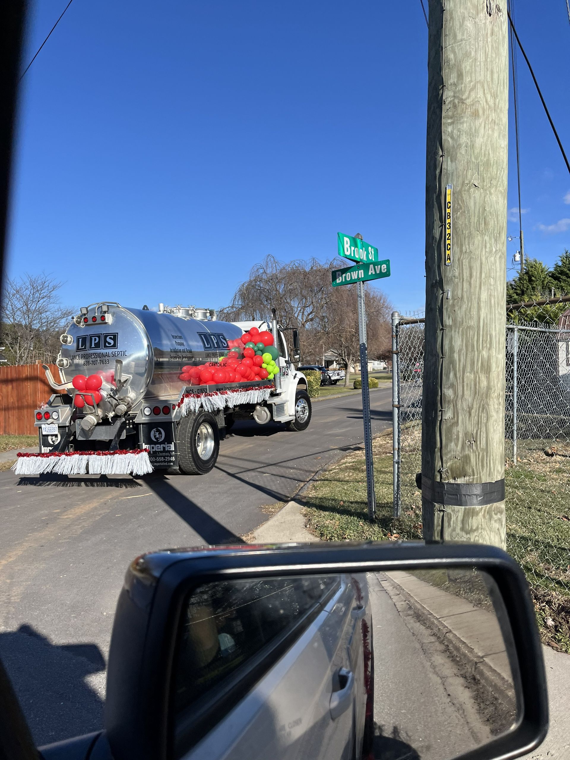 Red-and-white tanker truck turning at a street intersection beside a utility pole and road sign.