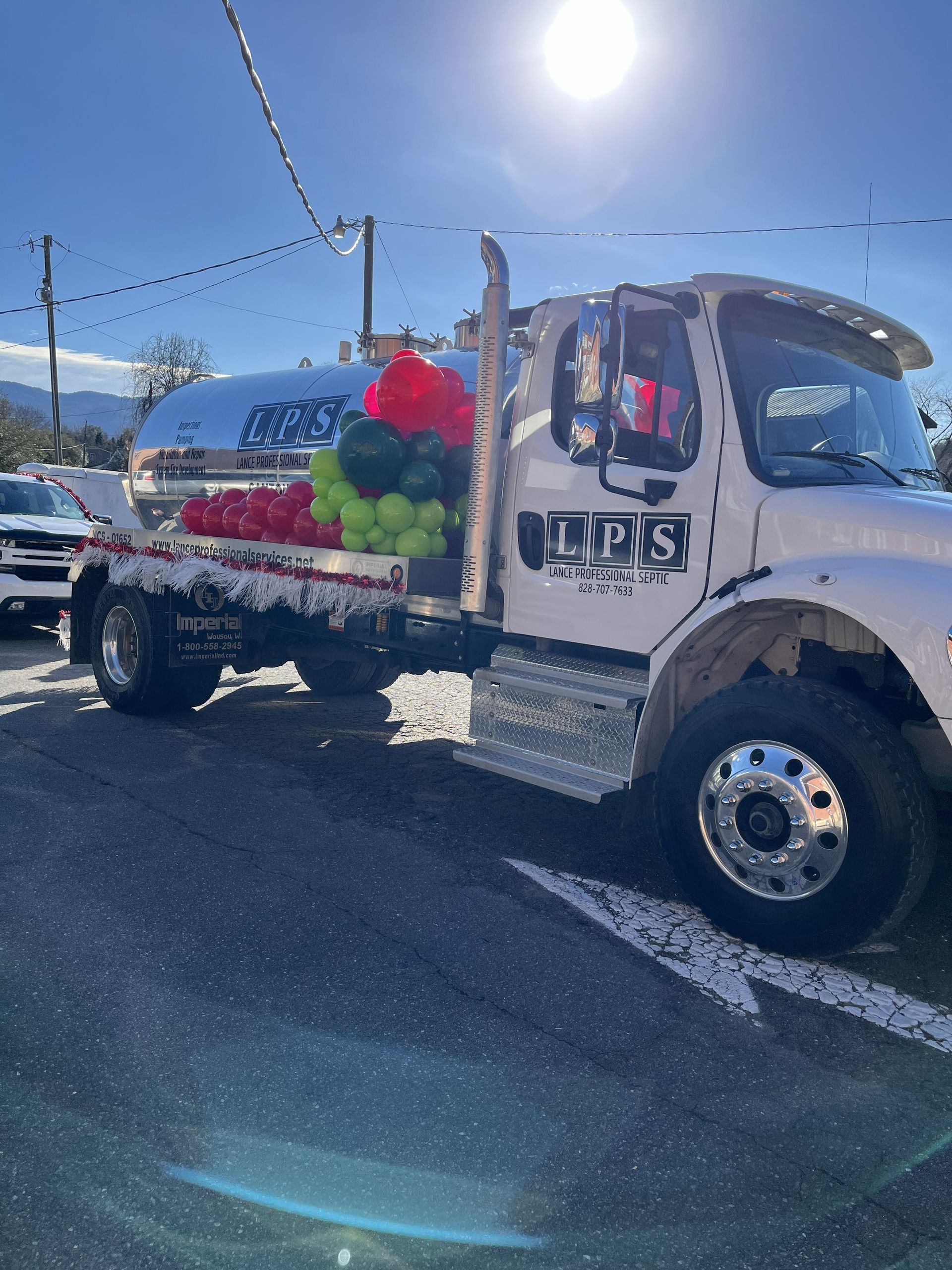 White produce truck loaded with green and red watermelons parked on a sunny street.