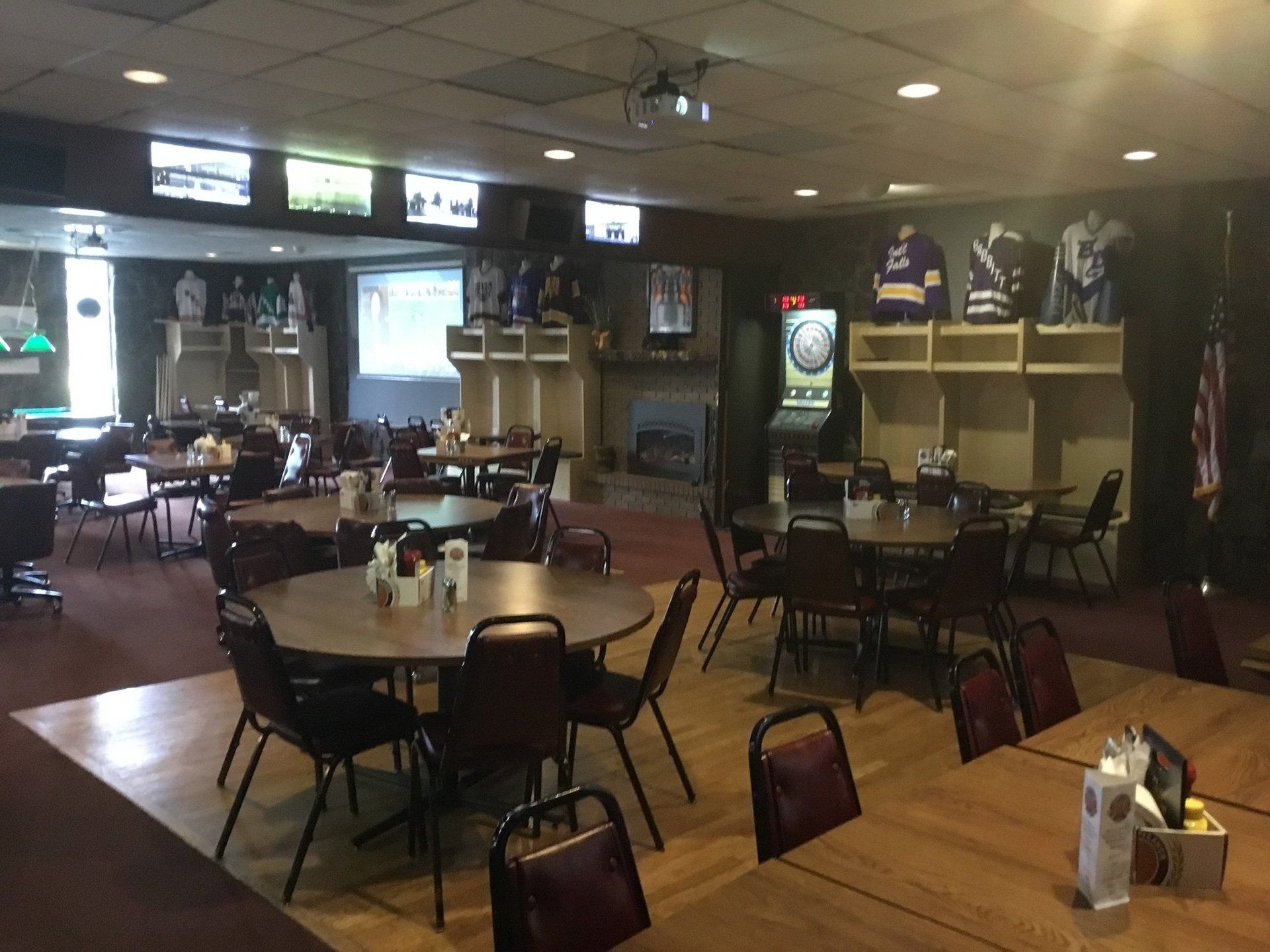 Empty restaurant dining area with tables, chairs, and booths under warm lighting