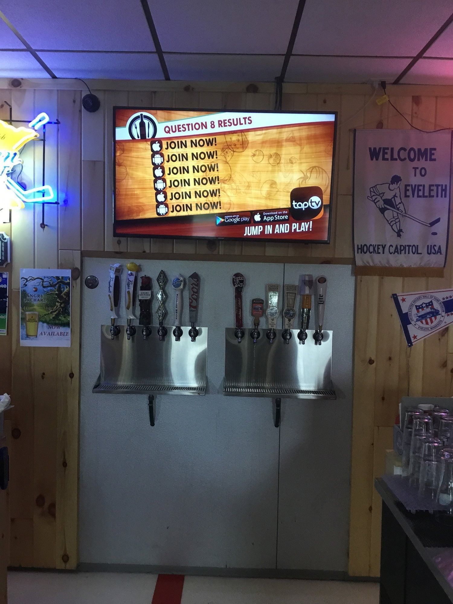 Indoor taproom with beer taps on a wall and a TV menu above them