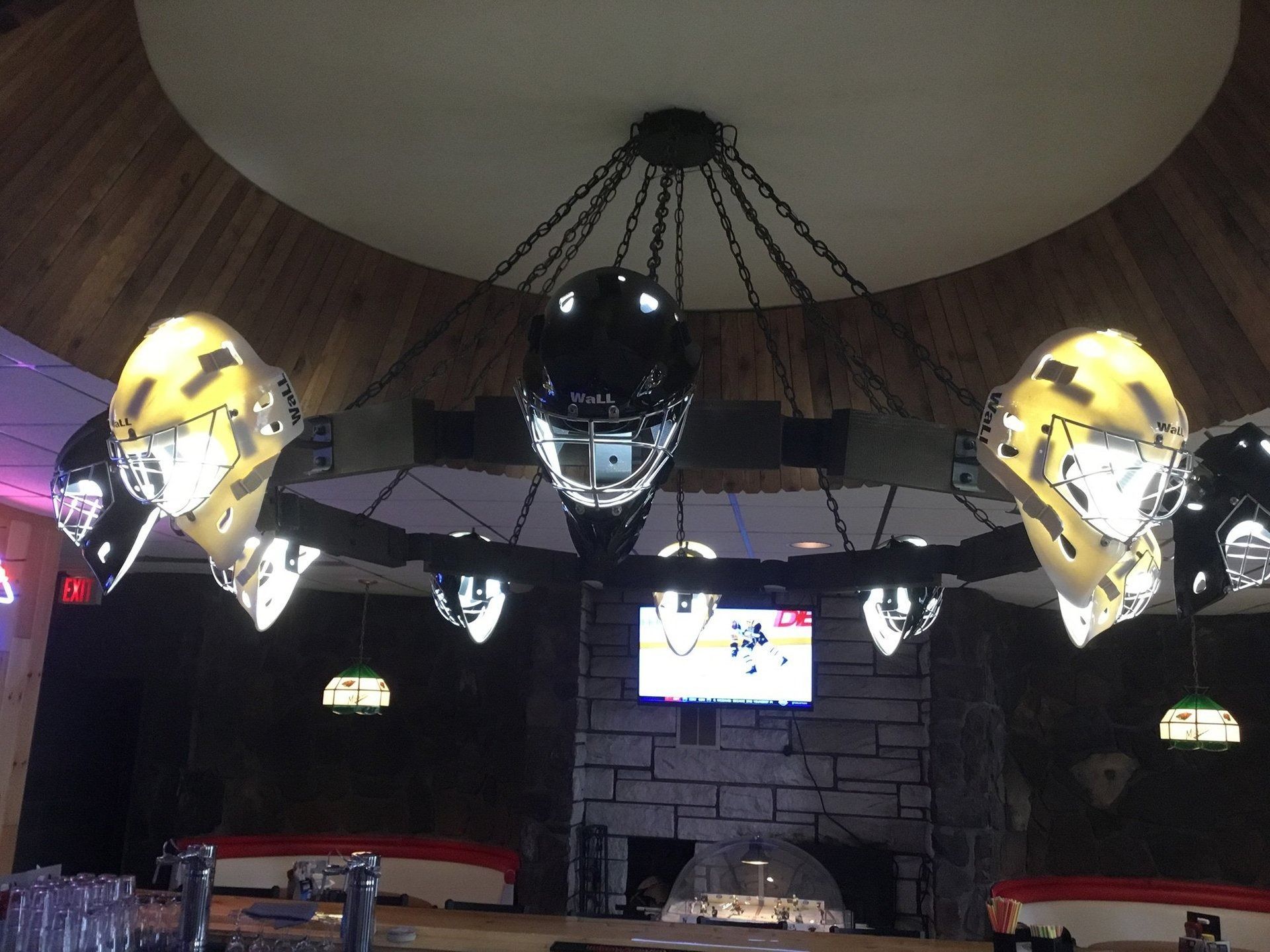 Three metallic motorcycle helmets hanging from the ceiling in a dim indoor venue