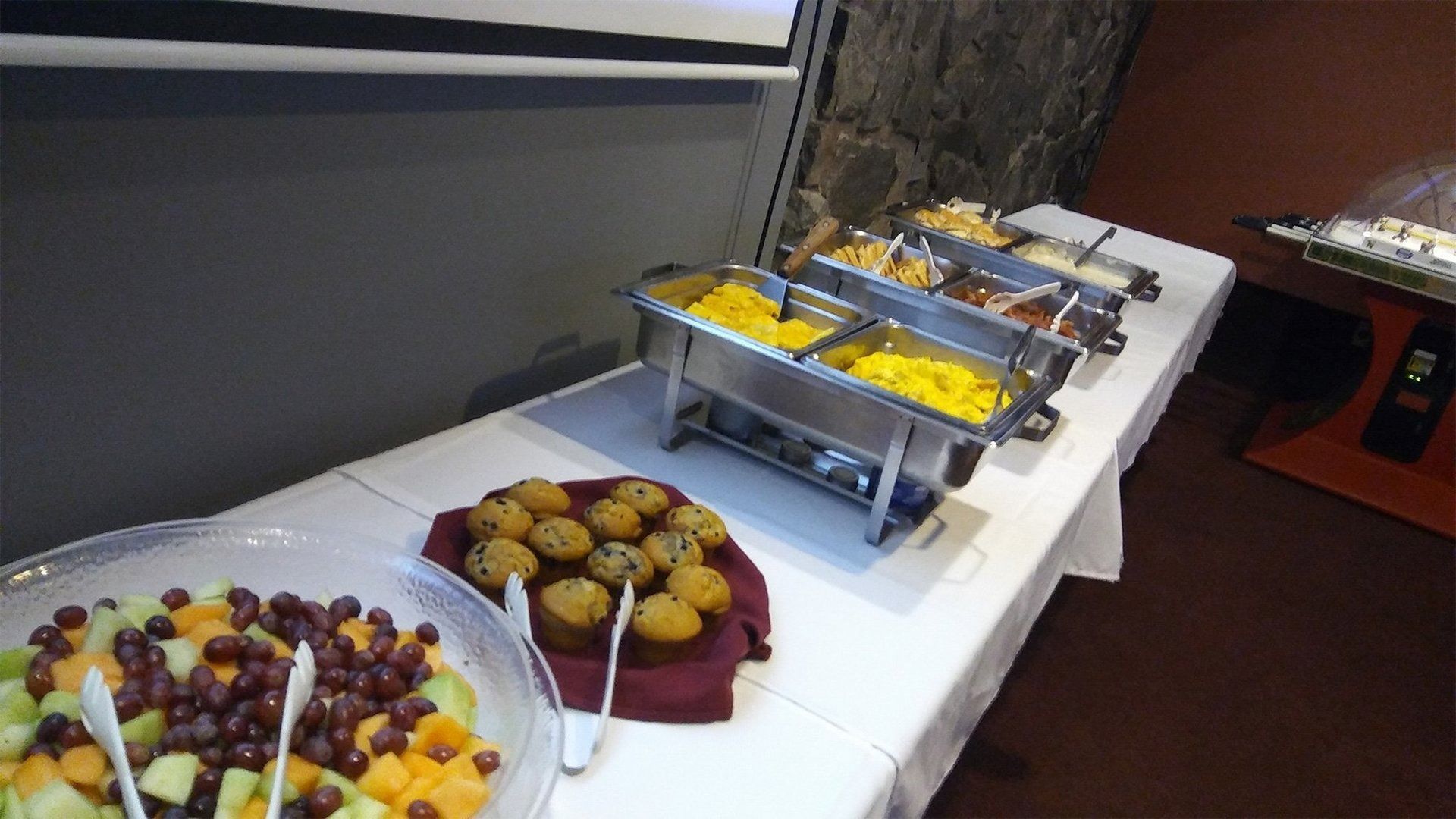 Buffet table with fruit bowls and hot trays of food in a banquet room