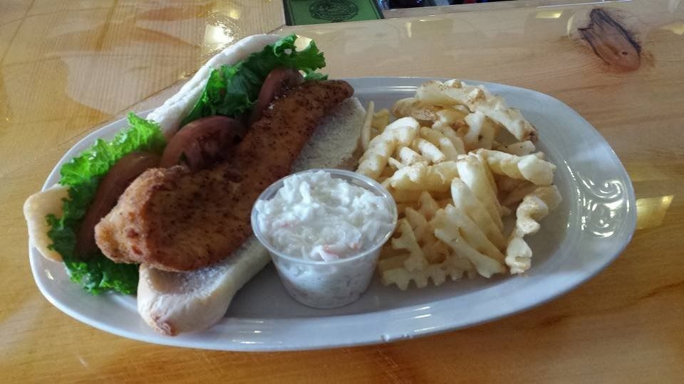 Plate of fried fish with lettuce garnish, tartar sauce, and crinkle-cut fries on a table