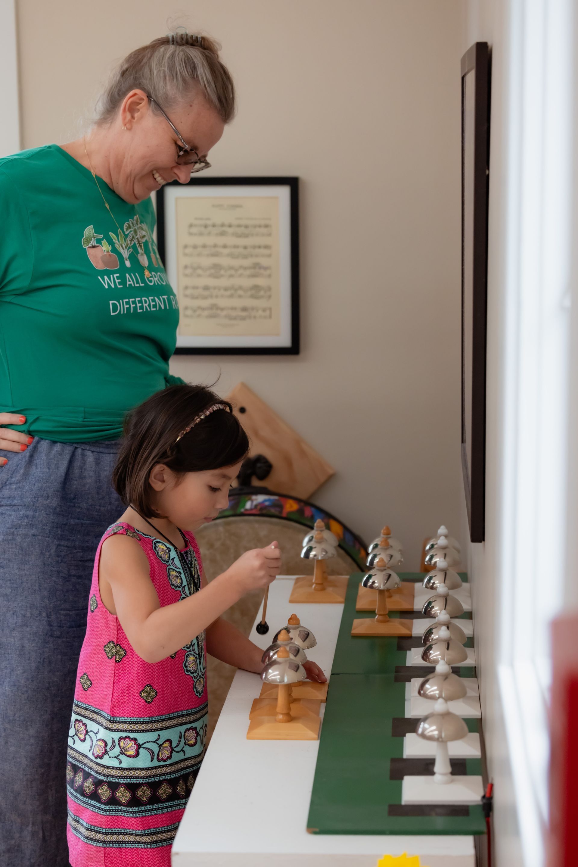 Child and adult working with the Montessori bells in a classroom.