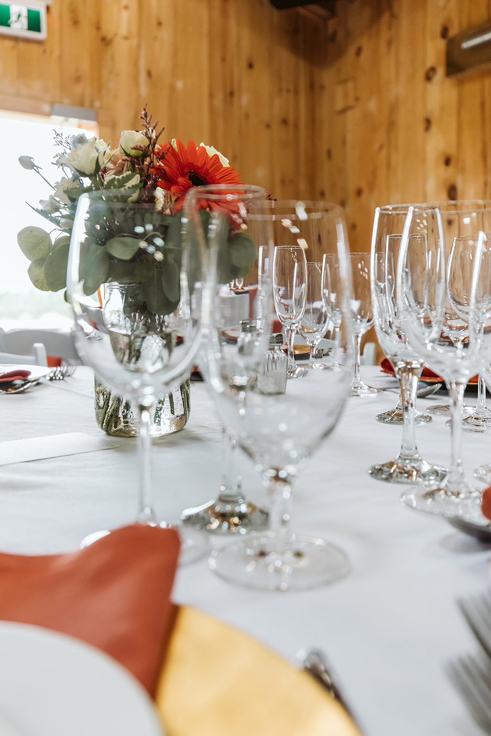 A table with a vase of flowers and wine glasses on it.
