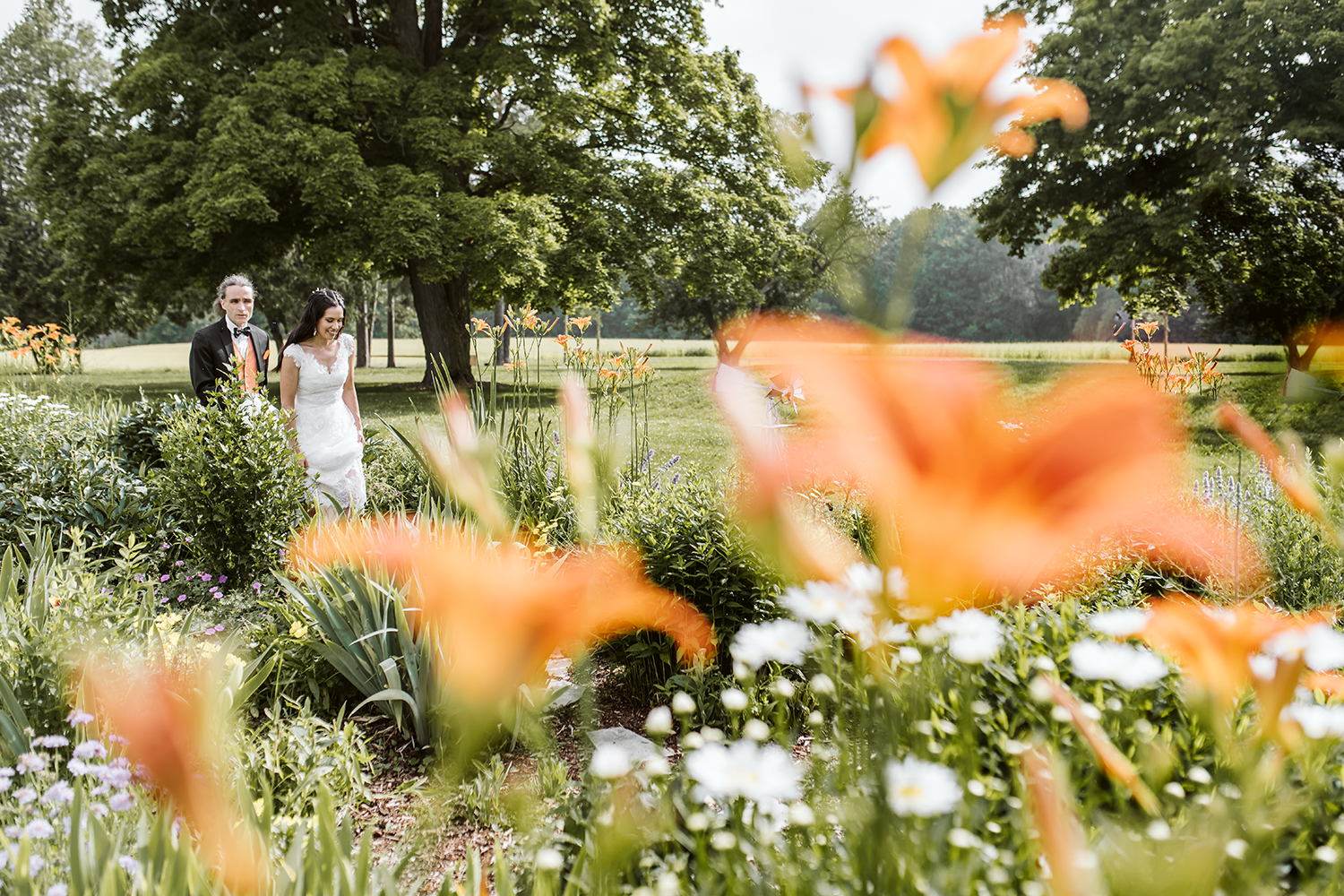 A bride and groom are standing in a field of flowers.