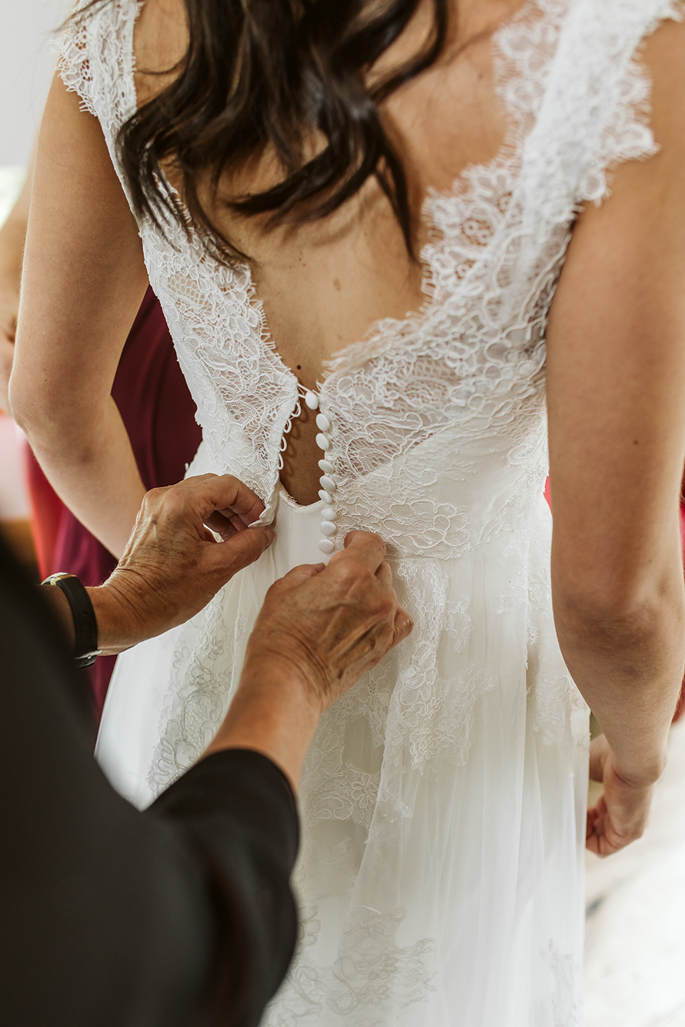 A woman is helping a bride with her wedding dress.