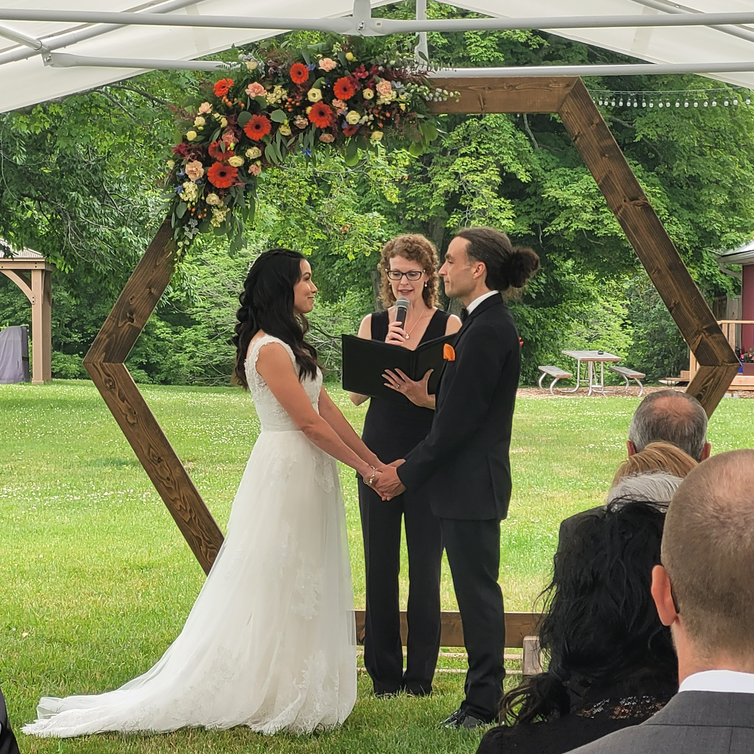 A bride and groom are holding hands during their wedding ceremony.