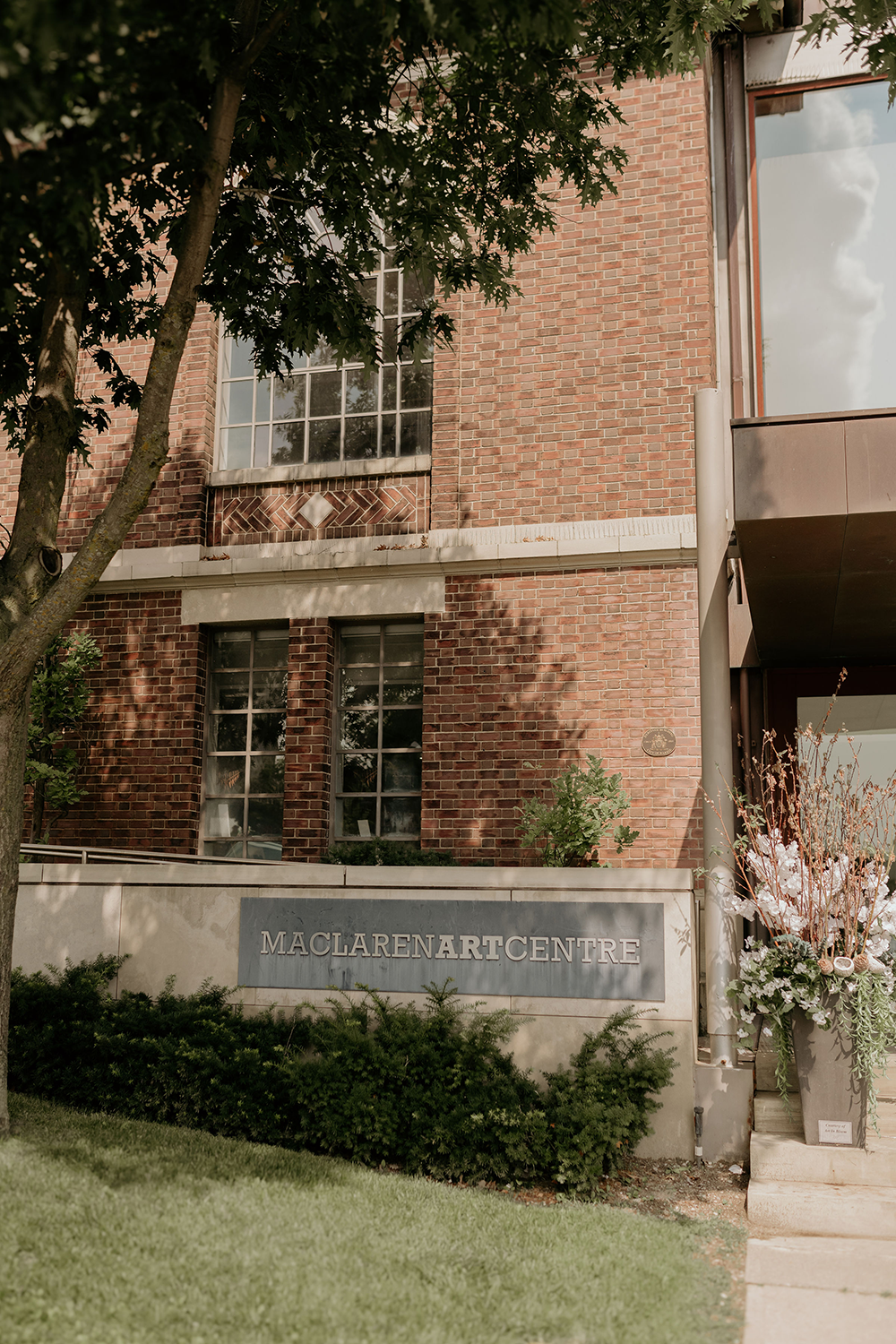 A brick building with a sign on the side of it and a tree in front of it.