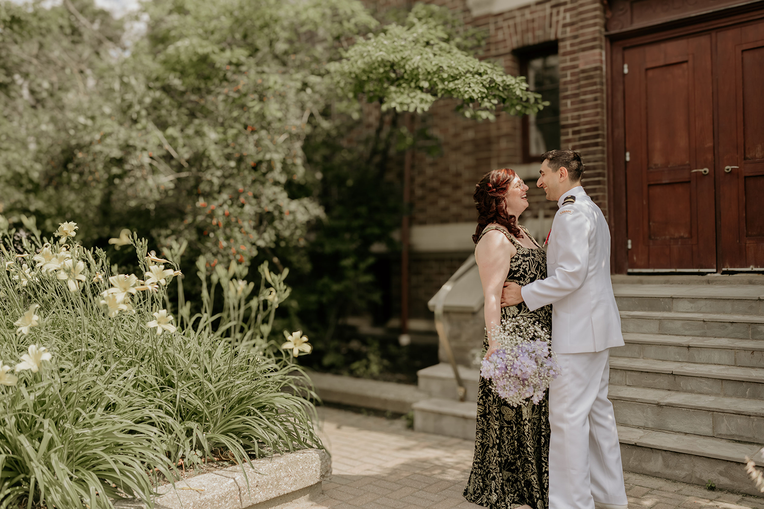 A man and a woman are kissing in front of a building.