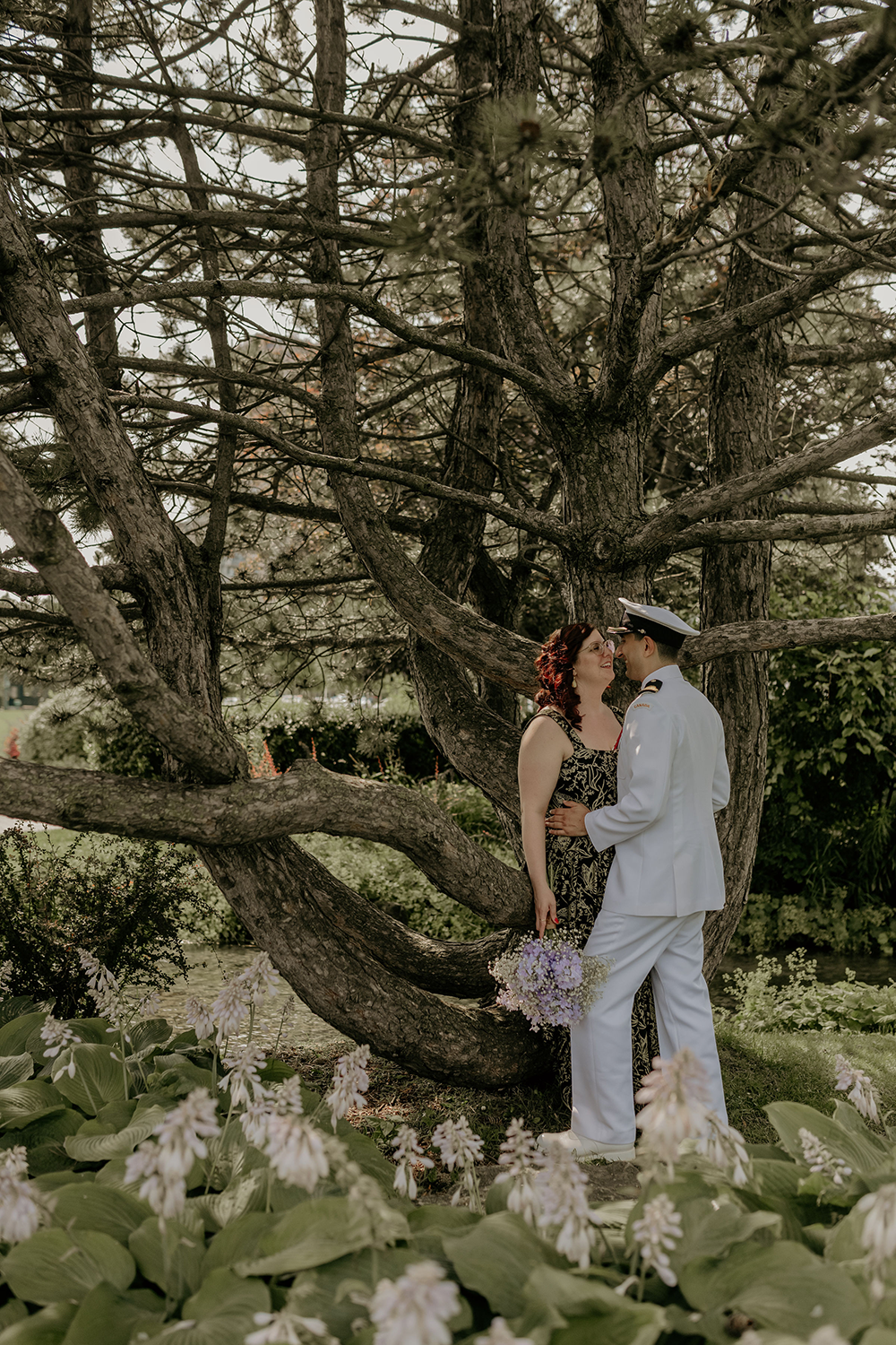 A man and a woman are kissing under a tree.