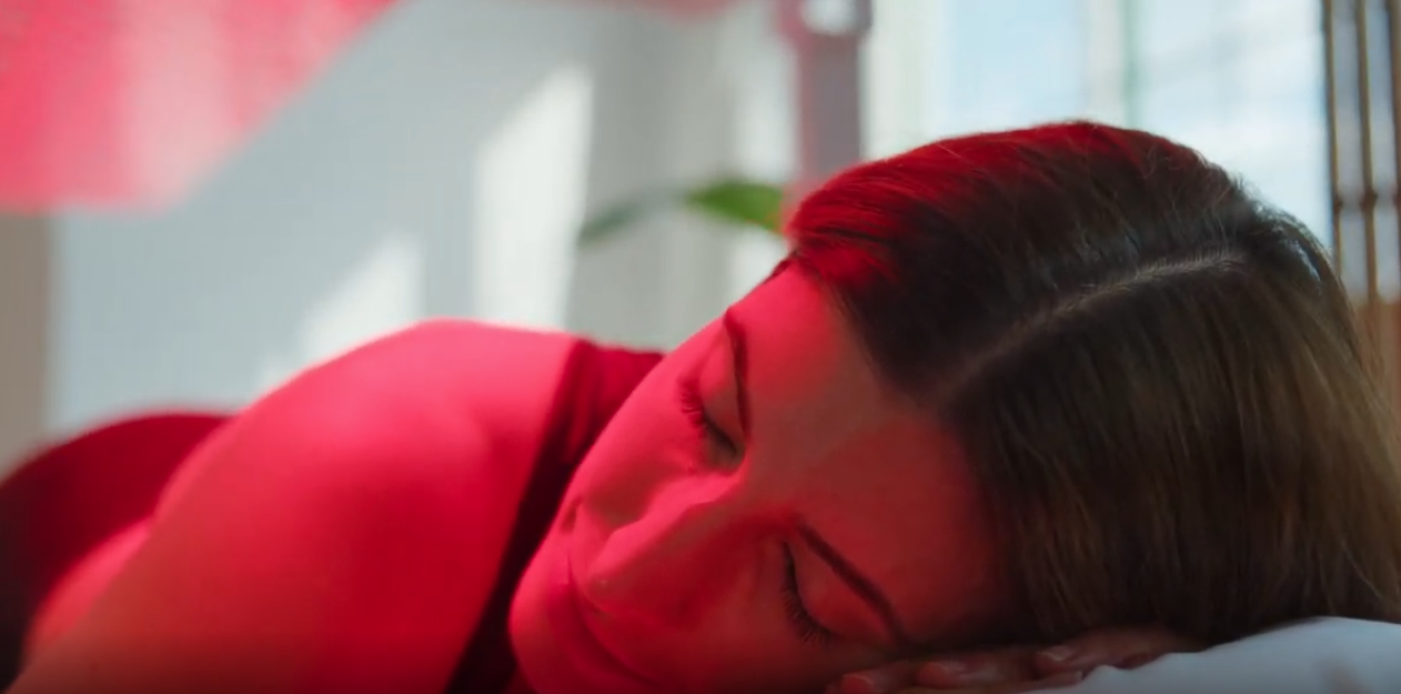 Person sleeping on a red-lit pillow, close-up view