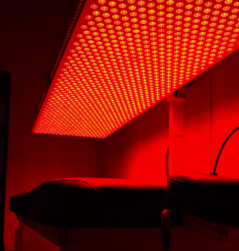 Red LED grow light panel illuminating a dark indoor room with furniture below