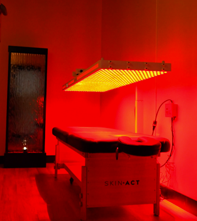 Red-lit therapy room with a treatment table and large heat lamp above it