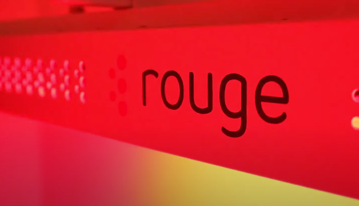 Red sign with the word “rouge” in black text on a pink and yellow background