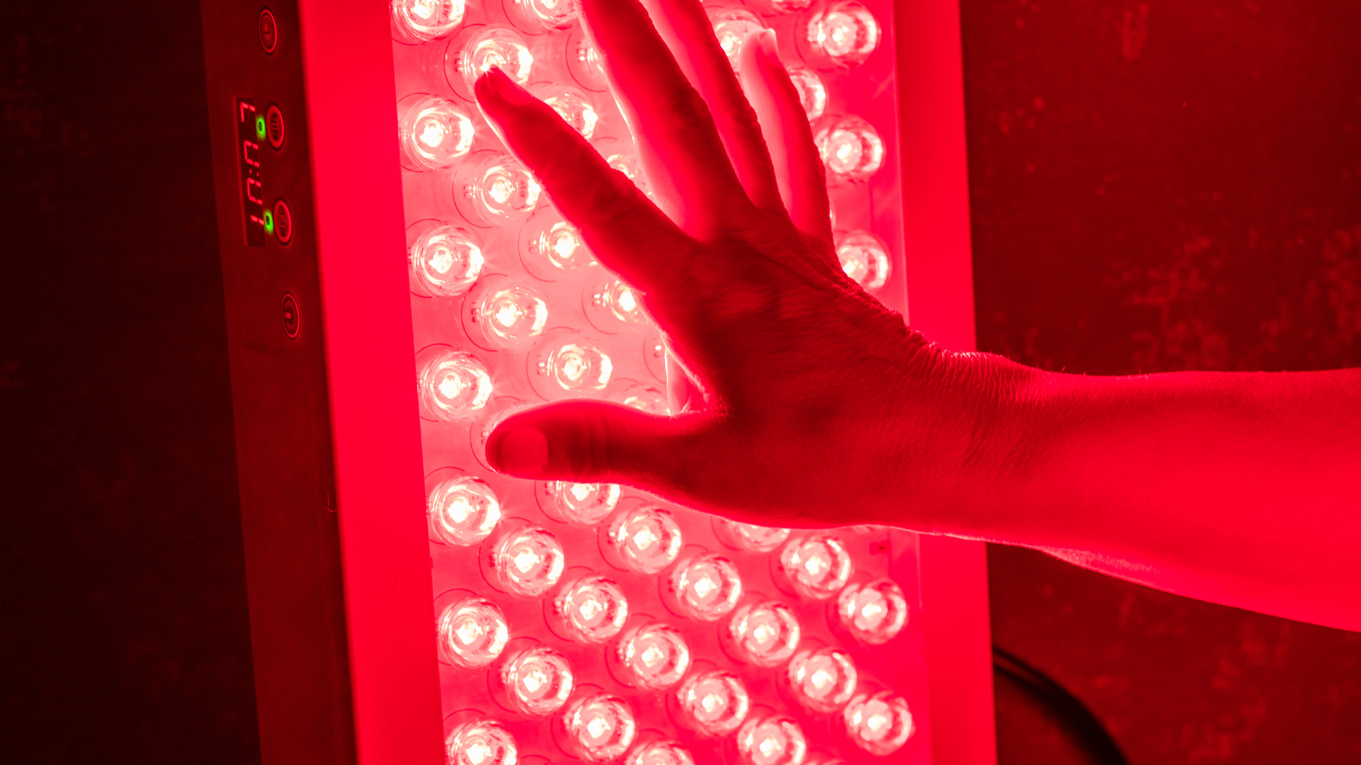 Hand touching a bright red LED light panel