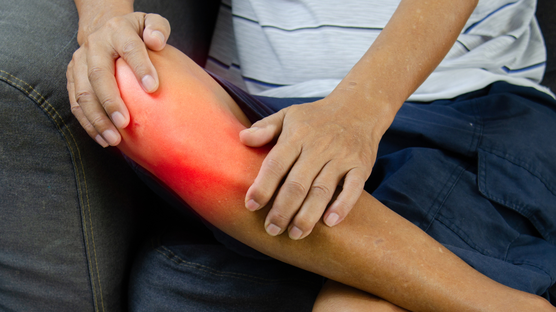 Person holding a glowing red calf, indicating leg pain or injury