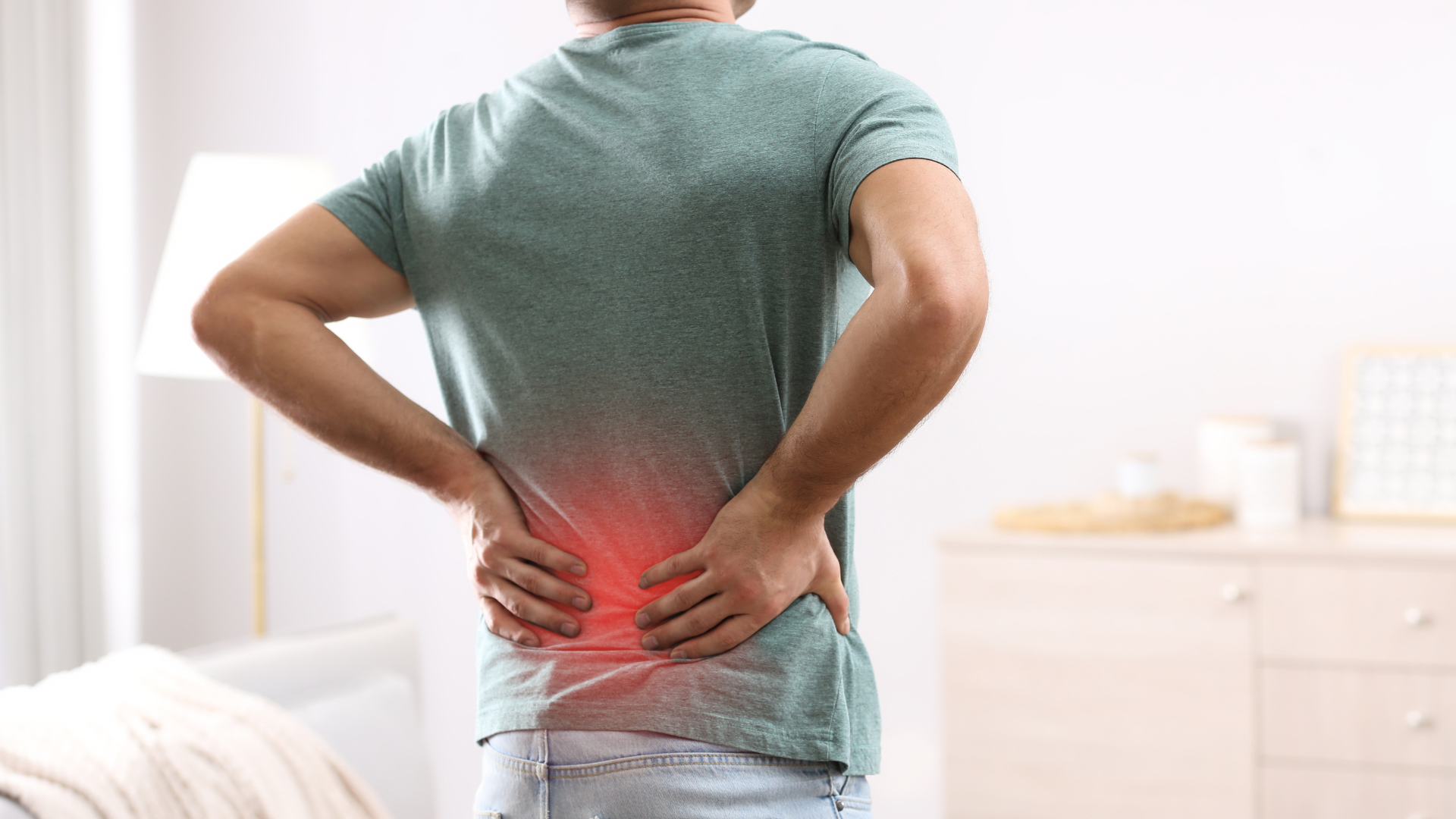 Person holding lower back with red pain highlight in a bright room