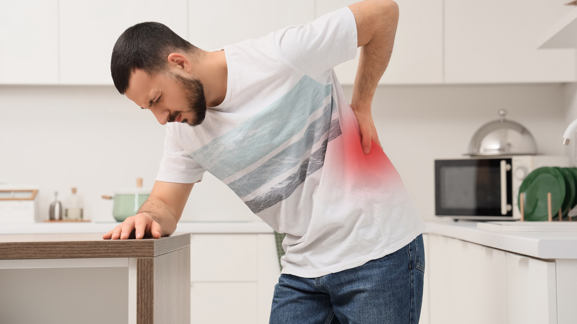 Person clutching lower back in a kitchen, showing pain with red highlight.