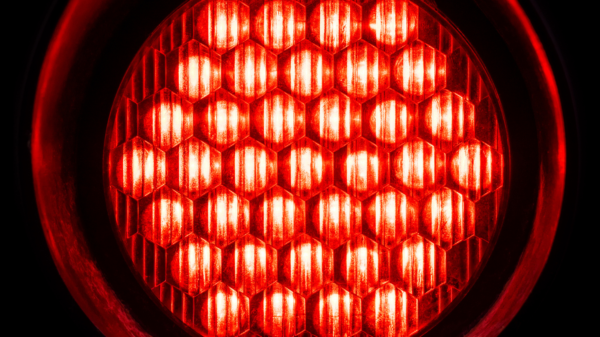 Close-up of a glowing red circular LED light with a honeycomb pattern