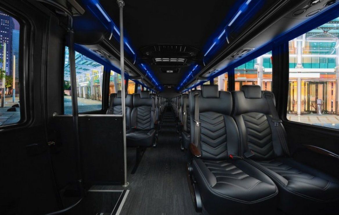 The inside of a bus with black seats and blue lights.