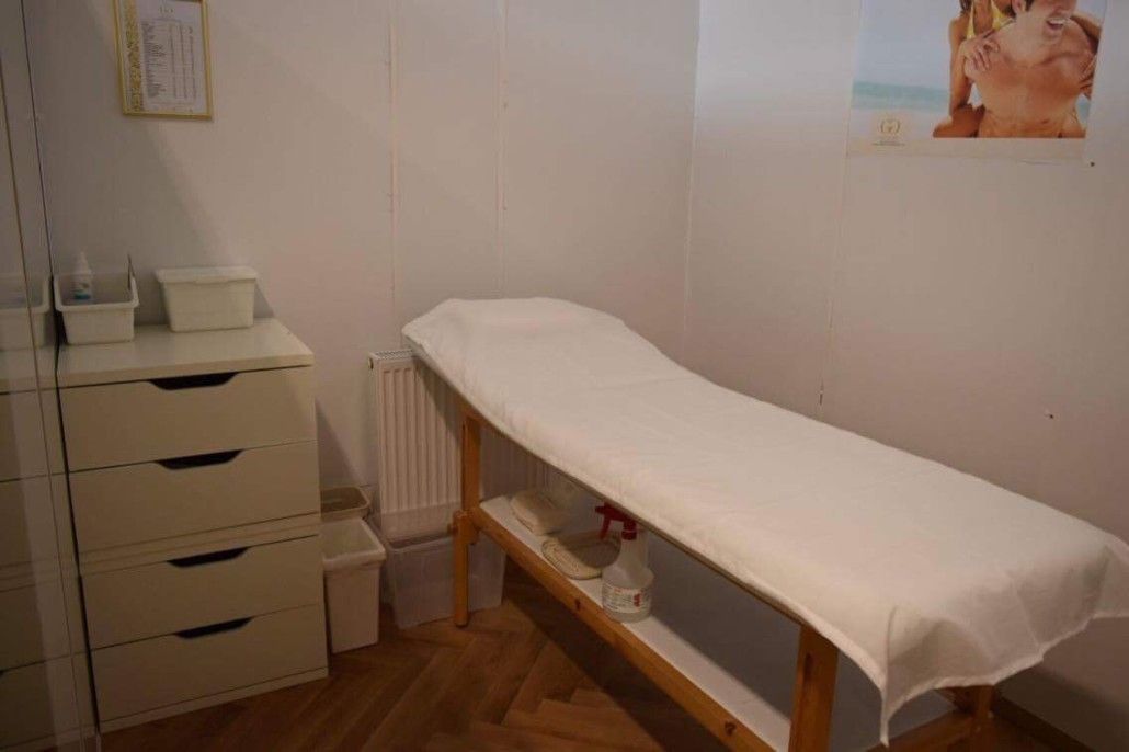 Ein Raum mit einem Massagetisch und einer Kommode.