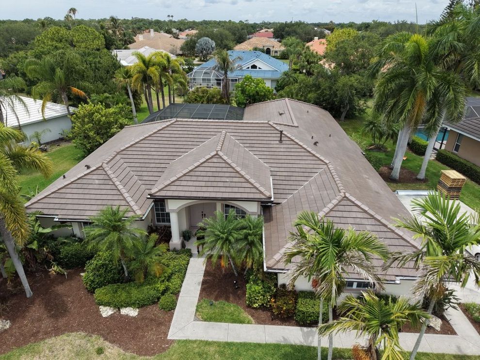 Aerial view of a tropical resort with a large thatched-roof building and a pool surrounded by palm trees.