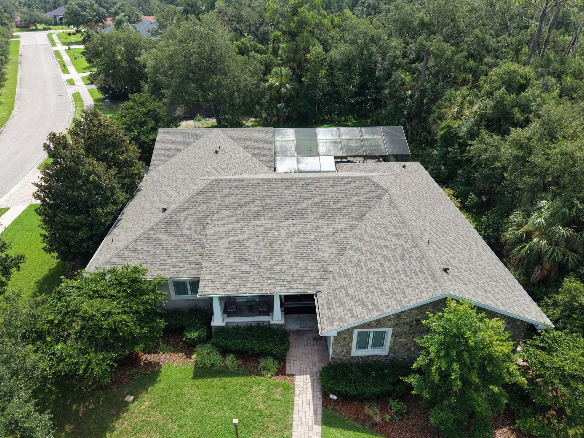 Aerial view of a light blue house with multiple roof sections and a backyard pool.