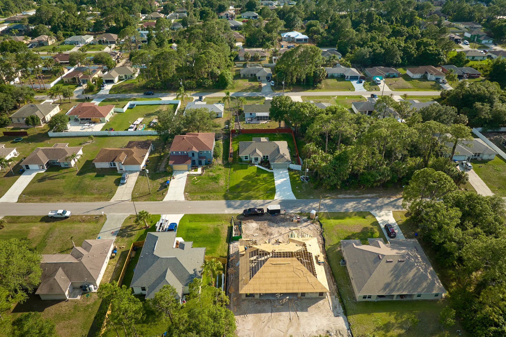 Aerial view of a suburban neighborhood with houses, streets, and trees under clear daylight