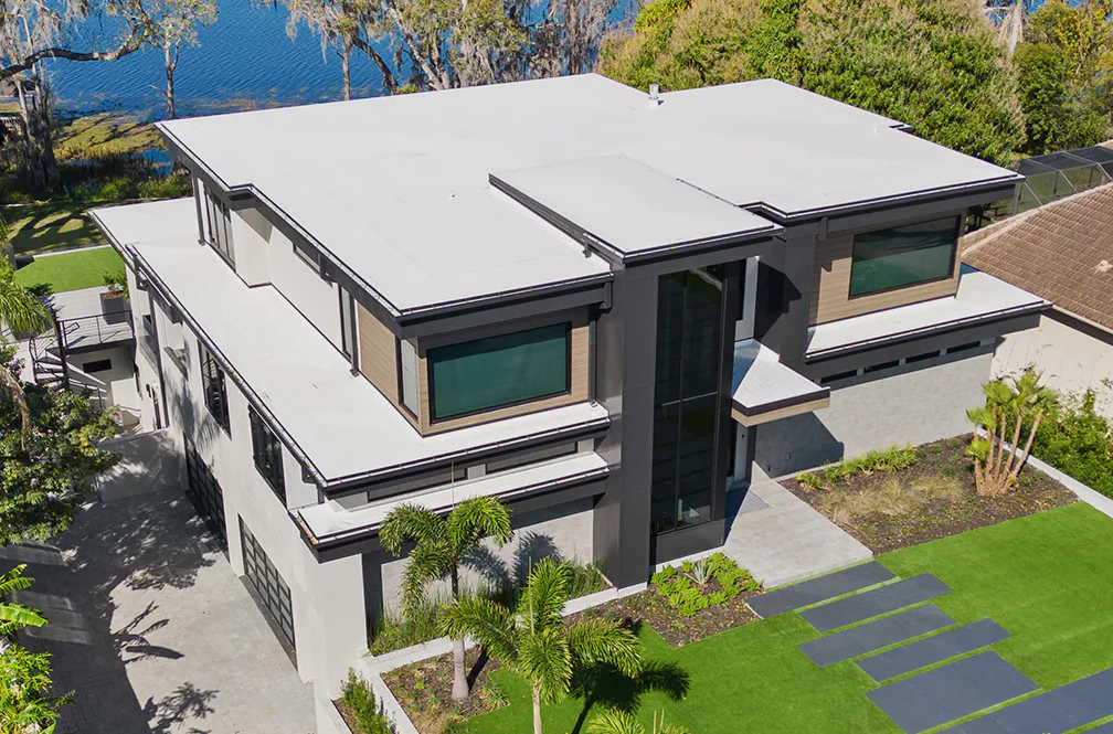 Modern two-story house with white exterior, dark roof, and landscaped front yard
