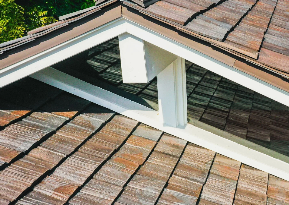 Rooftop dormer with white trim and brown shingles on a tiled roof