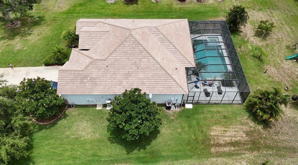 Aerial view of a house with a screened pool enclosure and green lawn surrounding it.