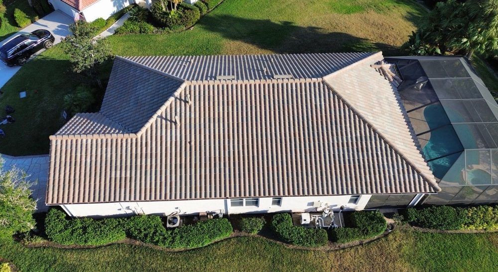 Aerial view of a beige-roofed house with a backyard pool and green lawn.